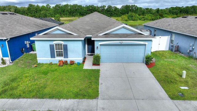 ranch-style home featuring a front lawn, a garage, and central AC unit