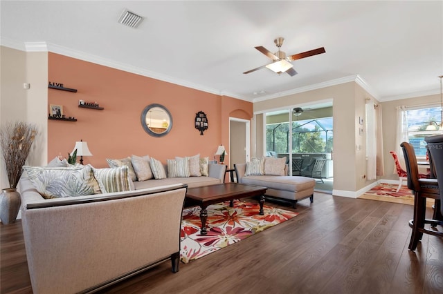 living room with ornamental molding, dark wood-type flooring, and ceiling fan