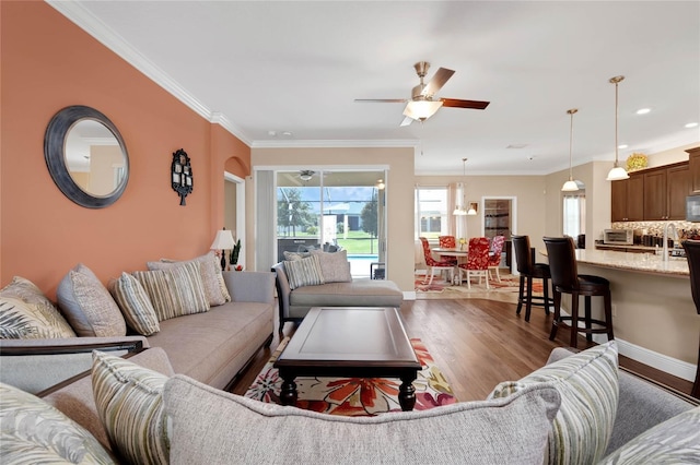 living room with ceiling fan, ornamental molding, dark hardwood / wood-style flooring, and sink