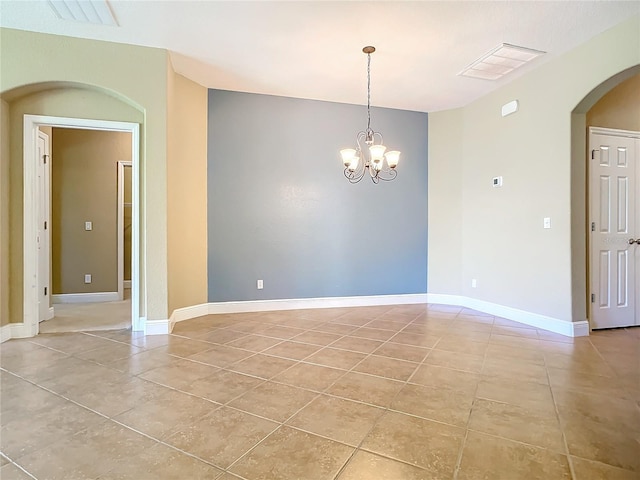 spare room with a notable chandelier and light tile patterned flooring