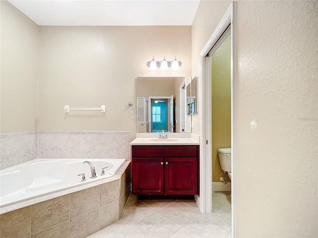 bathroom featuring tile patterned floors, tiled tub, vanity, and toilet