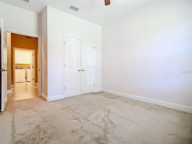 unfurnished bedroom featuring washing machine and dryer, ceiling fan, a closet, and light carpet