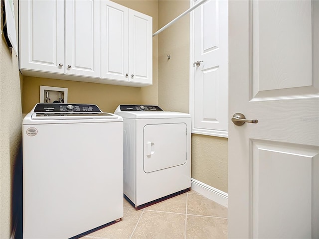 laundry room featuring cabinets, light tile patterned floors, and washing machine and clothes dryer