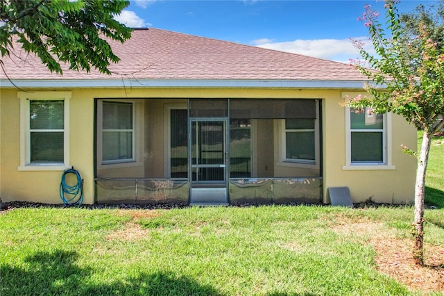 rear view of house featuring a yard and a sunroom