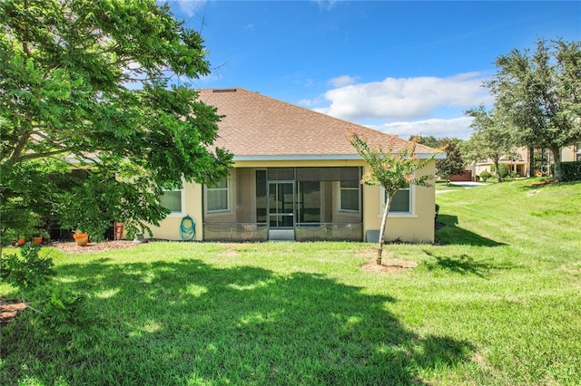 rear view of house with a lawn and a sunroom