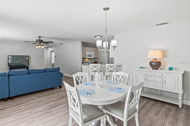 dining room featuring ceiling fan with notable chandelier, light hardwood / wood-style floors, and sink