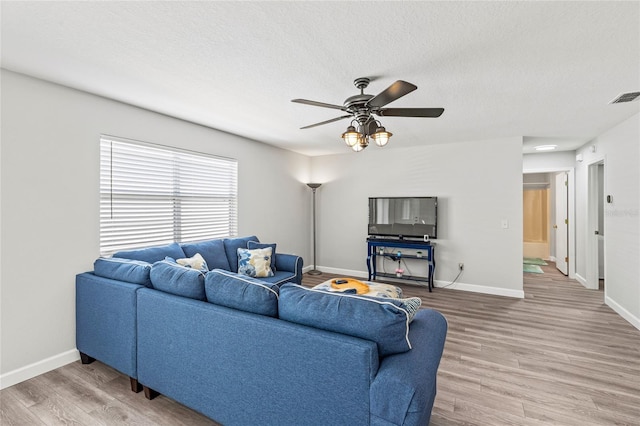 living room featuring hardwood / wood-style flooring, ceiling fan, and a textured ceiling