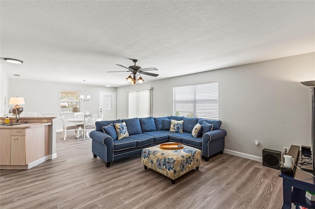 living room with hardwood / wood-style flooring, ceiling fan, sink, and a textured ceiling