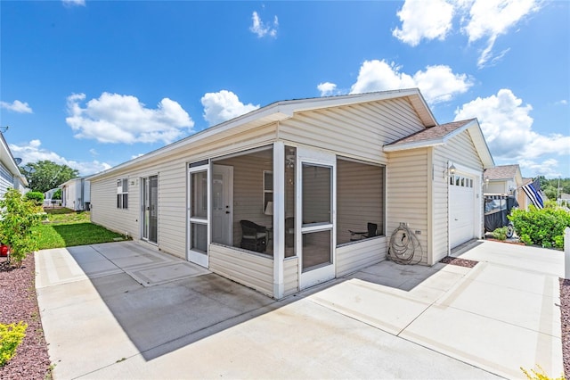 rear view of property with a sunroom and a garage