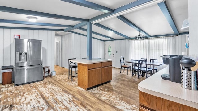 kitchen with lofted ceiling with beams, a breakfast bar area, light hardwood / wood-style floors, and stainless steel fridge with ice dispenser