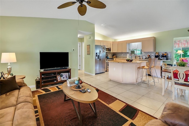 living room featuring light tile patterned floors, vaulted ceiling, and ceiling fan