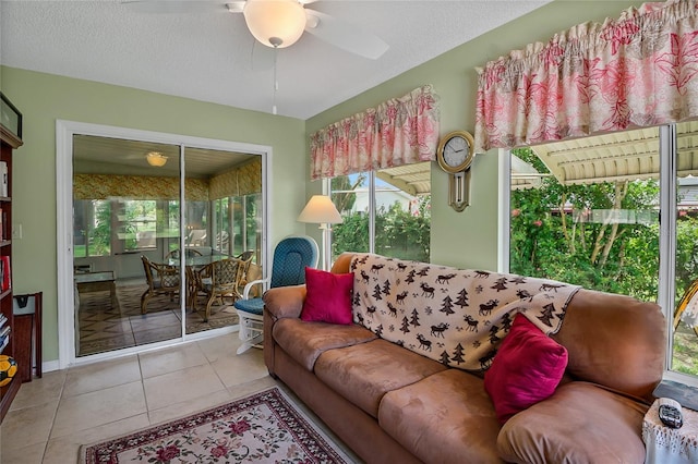 living room with ceiling fan, light tile patterned floors, and a textured ceiling