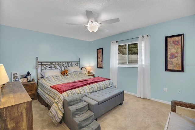 bedroom featuring light carpet, a textured ceiling, and ceiling fan