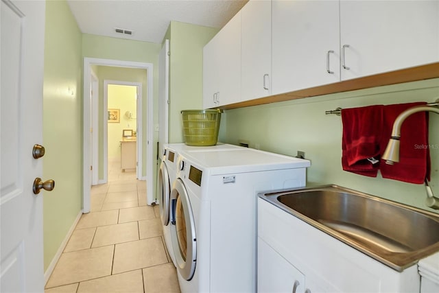 clothes washing area with cabinets, sink, separate washer and dryer, a textured ceiling, and light tile patterned flooring