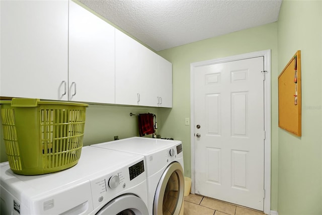 laundry area featuring cabinets, light tile patterned floors, a textured ceiling, and separate washer and dryer