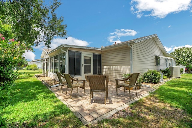 rear view of house featuring a patio area, a sunroom, a yard, and central AC unit