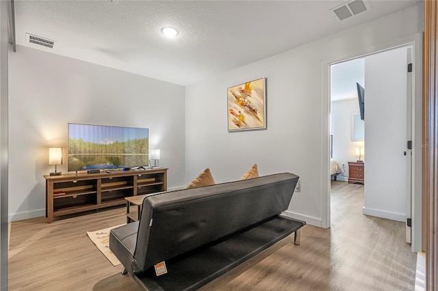 living room featuring a textured ceiling and light hardwood / wood-style floors