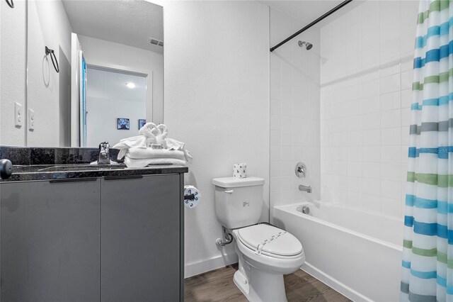 full bathroom with wood-type flooring, shower / bath combination with curtain, toilet, and vanity