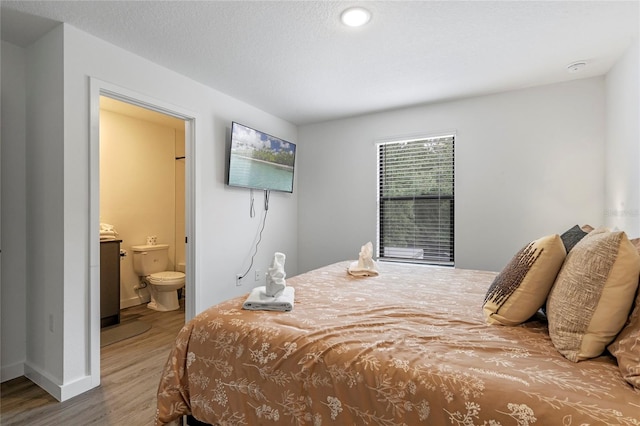 bedroom with hardwood / wood-style floors and ensuite bath