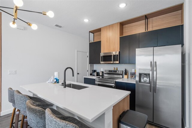 kitchen with stainless steel appliances, sink, a kitchen island with sink, dark hardwood / wood-style floors, and a breakfast bar