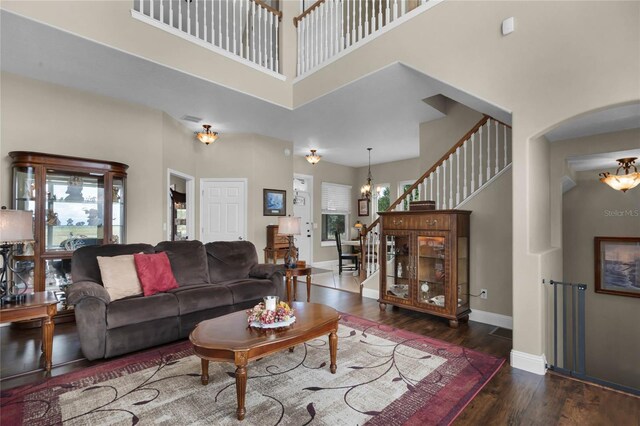 living room with an inviting chandelier, hardwood / wood-style floors, and a high ceiling