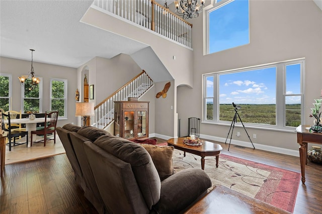 living room with a wealth of natural light, an inviting chandelier, and hardwood / wood-style floors