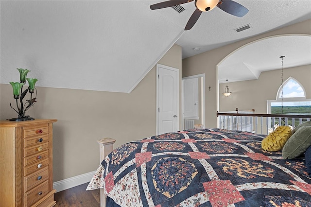 bedroom with vaulted ceiling, a textured ceiling, ceiling fan, and dark hardwood / wood-style floors