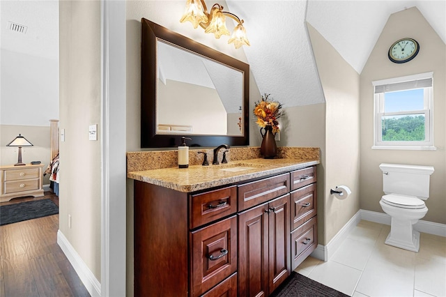 bathroom featuring tile flooring, lofted ceiling, a textured ceiling, vanity, and toilet