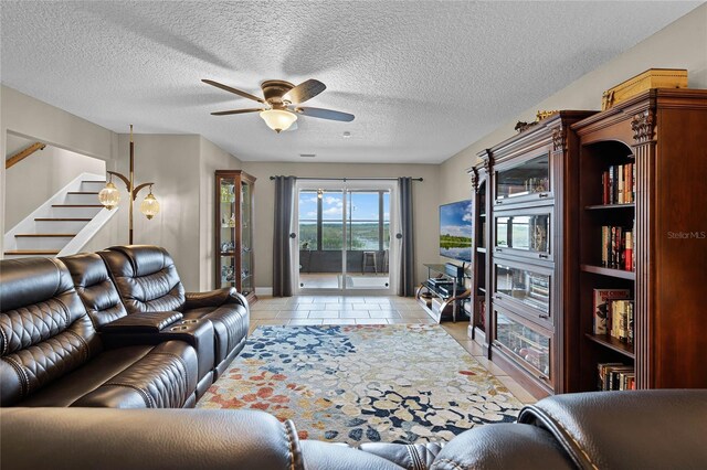 living room featuring ceiling fan, a textured ceiling, and light tile flooring