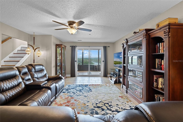 living room featuring ceiling fan, light tile patterned floors, and a textured ceiling