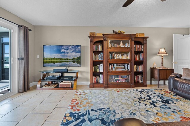 tiled living room with ceiling fan and a textured ceiling