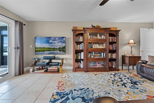 tiled living room featuring ceiling fan, a textured ceiling, and a wealth of natural light