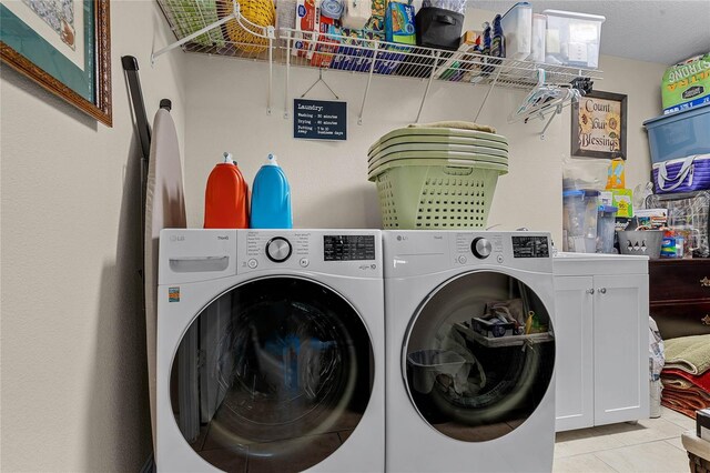 clothes washing area featuring separate washer and dryer and light tile floors