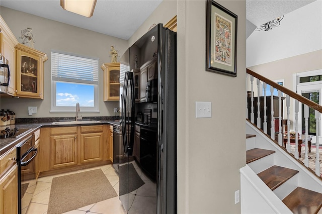 kitchen featuring black appliances, sink, light tile flooring, and light brown cabinets