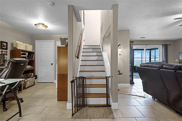 stairs featuring a textured ceiling and light tile flooring