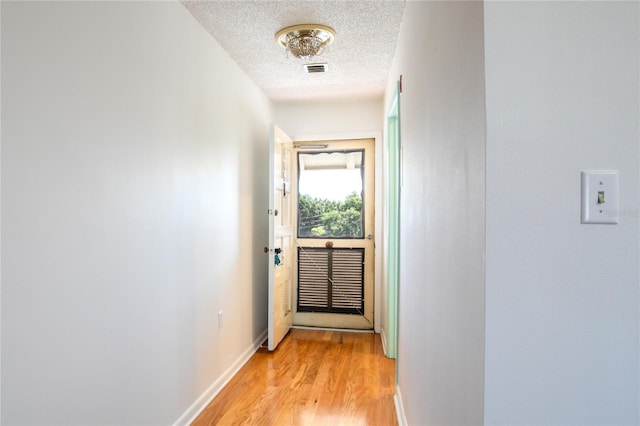 corridor featuring light hardwood / wood-style flooring and a textured ceiling