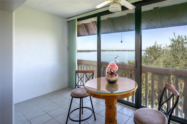 sunroom / solarium featuring ceiling fan and a water view