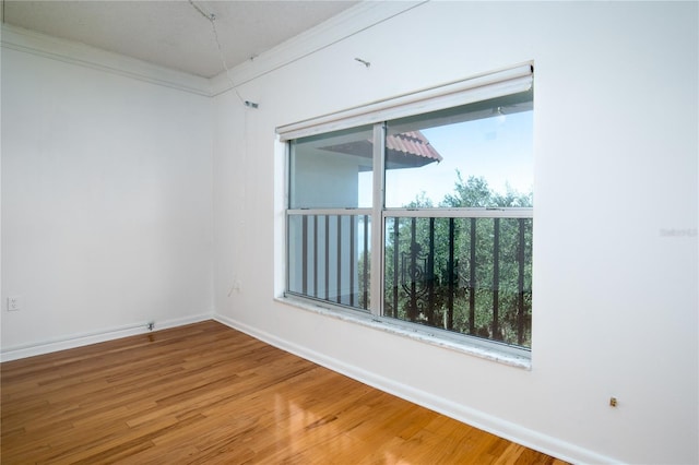 empty room featuring ornamental molding and hardwood / wood-style floors