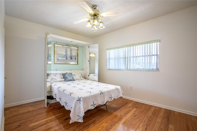 bedroom featuring ceiling fan, hardwood / wood-style floors, and a textured ceiling