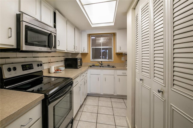 kitchen featuring sink, light tile patterned floors, stainless steel appliances, tasteful backsplash, and white cabinets