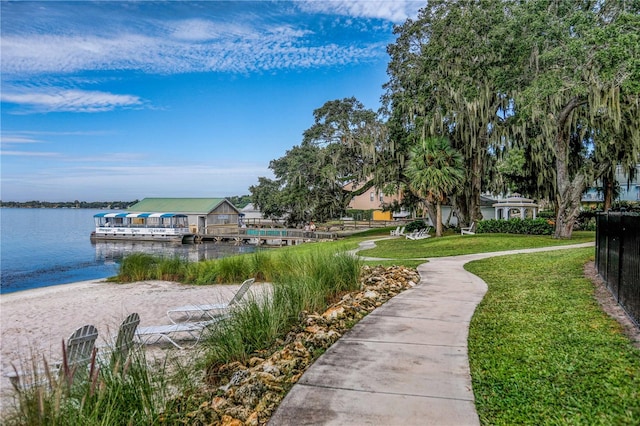 view of dock with a water view and a lawn