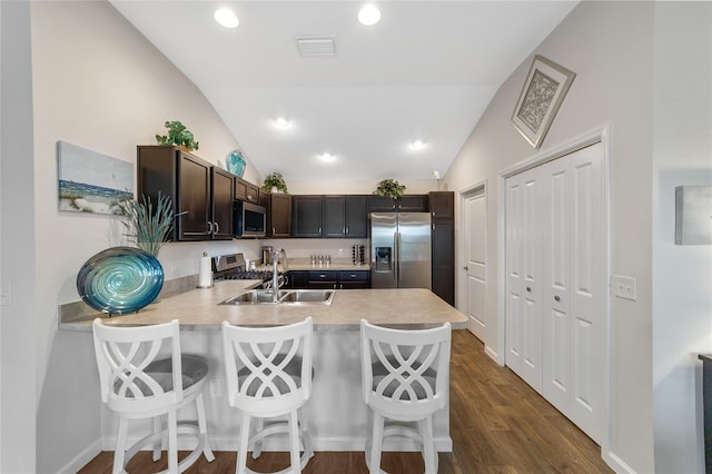 kitchen featuring dark brown cabinets, kitchen peninsula, appliances with stainless steel finishes, and vaulted ceiling