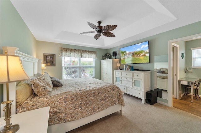 carpeted bedroom with a tray ceiling and ceiling fan