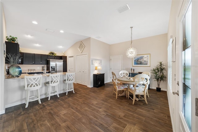 dining room featuring lofted ceiling, dark wood-type flooring, and a notable chandelier