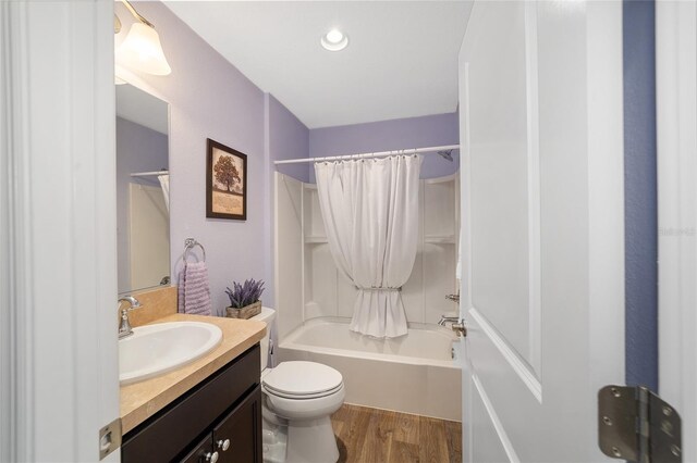 full bathroom with hardwood / wood-style flooring, shower / bath combo with shower curtain, vanity, and toilet