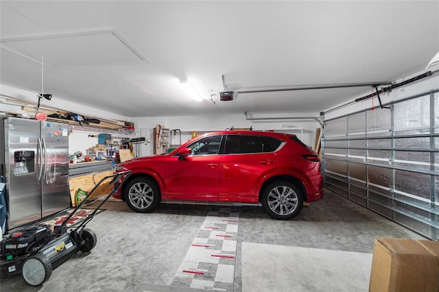 garage with stainless steel fridge with ice dispenser and a garage door opener