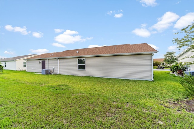 rear view of property featuring cooling unit and a lawn