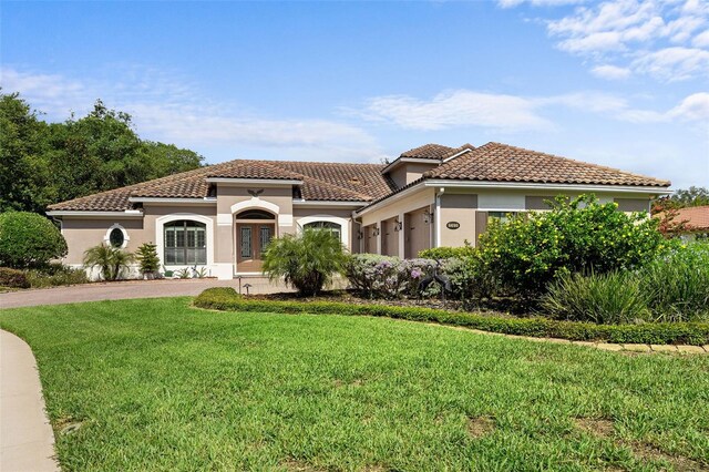 mediterranean / spanish house featuring a front yard and a garage