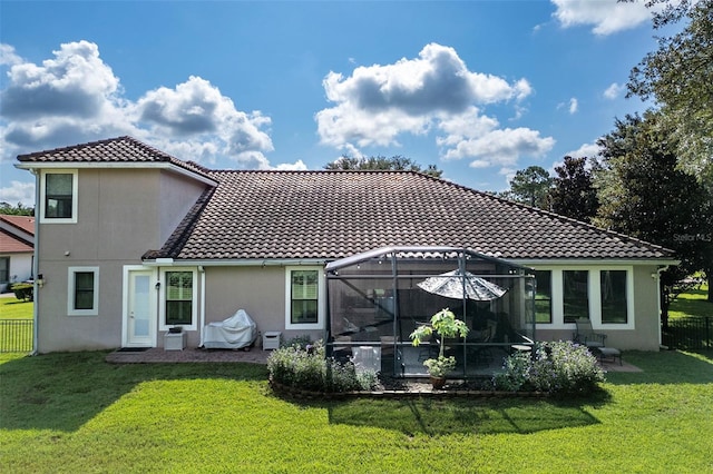 rear view of house with a patio area, glass enclosure, and a lawn