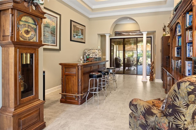 bar featuring ornate columns, crown molding, and light tile patterned floors